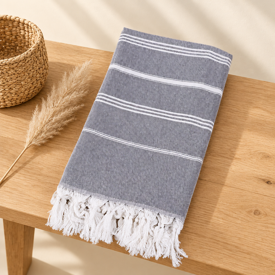 Grande serviette de plage style turc grise pliée sur fond crème
