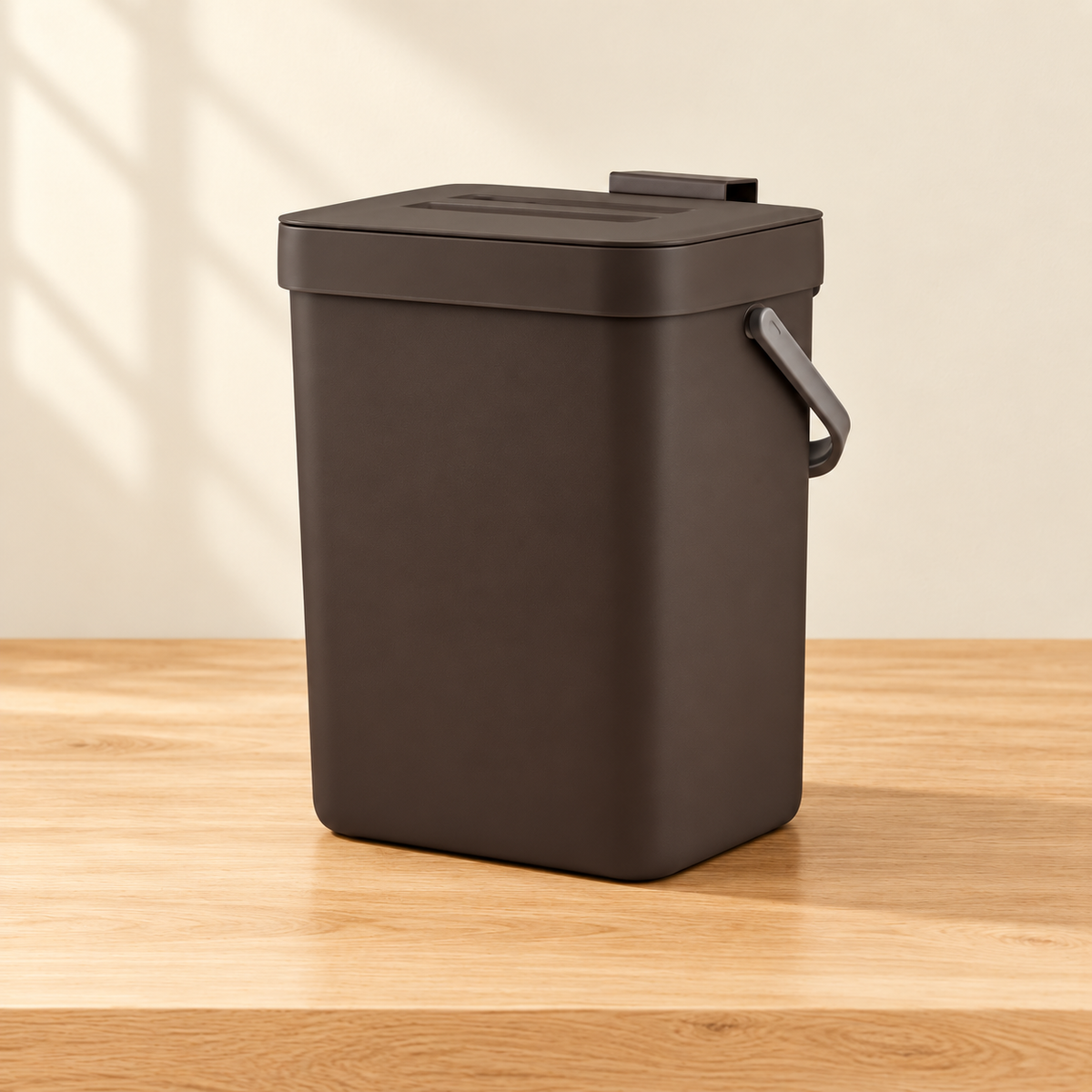 Countertop compost bin on a light wood surface